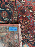Underside view of decorative botanical details with aquamarine and rust tones on Persian Heriz rug.