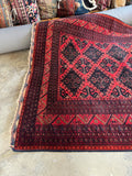 One end view of tribal motifs on a vintage Afghan rug.