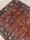 Handwoven Heriz rug featuring aquamarine blue accents on a rust-toned ground.