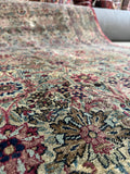 Distressed antique Persian wool rug with time-earned wear and muted berry tones.