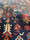 Detail of antique Caucasus rug with small scale tribal motifs arranged in rows on a deep blue ground.
