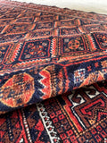 Vintage Baluch scatter rug top-down view showing a soft, floppy handle and rich vegetable-dyed wool colors.