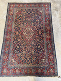 Durable hand knotted Persian rug with warm red botanical borders, measuring 4 foot 4 inches by 6 foot 9 inches.