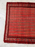 Vegetable dyed wool antique Persian rug with saturated red field and tribal motifs.