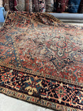 Vintage rug with intricate patterns on a warm red background.