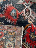 Antique wool rug detail highlighting hand-woven knots, worn low pile, and durable edge binding.