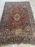 Antique Persian Shiraz rug from the 1920s with large central medallion and tribal motifs.