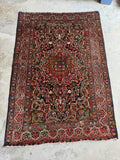 1920s Persian Bakhtiari rug with tribal floral motifs, low pile vegetable dyed wool area rug.