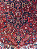 Close up view of an Antique Heriz rug featuring serrated leaves, palmettes, and angular vines throughout.