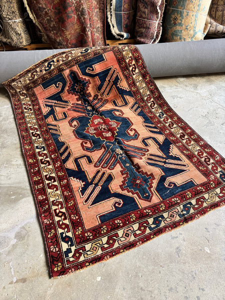 Full view of antique 1920s Persian tribal rug with abrash pink field.