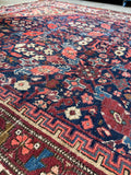 Persian rug with intricate multicolor floral pattern on navy field.