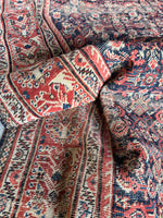 Low pile Persian rug from 1920s with scattered wear and aged patina.