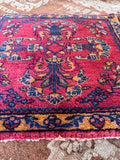 Small antique wool table rug with floral border in berry pink and aqua blue.
