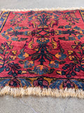 Small Persian accent rug showing close-up of fringe and rich vegetable dyes.