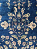 Antique Turkish wool rug with navy field, flowering vines, and soft aged color palette.