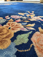 Close up view of floral motifs in a 1930s Art Deco Chinese rug featuring an open field design in deep blue.