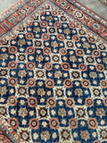 Vintage Persian Veramin area rug showing repeating rosettes and vine lattice across a rich blue field.