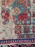 Hand-knotted antique wool rug from the Caucasus region with distressed age-worn patina and character.