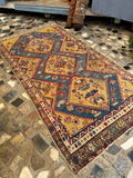 Distressed 1800s Persian rug flat-lay view with an unusual yellow and aqua blue color palette.
