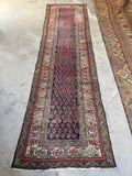 Worn Persian runner with scattered wear and solid handmade construction.