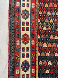 Antique Caucasian runner with rows of stylized flowers and angular village symbols.