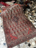Antique Persian Ferahan rug with paisley field and central medallion on mosaic tile floor