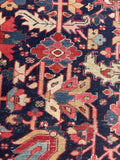 Close up of 9x12 navy blue antique Persian Heriz rug styled in a living room with bold geometric tribal pattern.