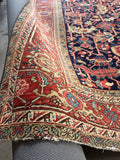 9x12 navy blue Persian Heriz area rug featuring bold tribal geometric motifs and a rust terracotta border.