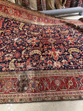 9x12 navy blue wool Heriz rug with angular botanical motifs and rust terracotta accents.