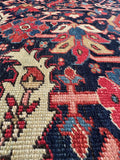 Close up of 9x12 navy blue antique Persian area rug with bold tribal artwork and low wool pile.