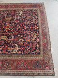 One end of 9x12 navy blue antique Persian Heriz rug handmade with vegetable-dyed wool and bold tribal artistry.
