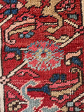 Close up of border band of a 9x12 navy blue antique Persian Heriz rug with a bold geometric pattern and tribal botanical motifs.