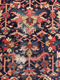 Close up of 9x12 navy blue antique wool Heriz area rug with vegetable dyes and graphic geometric composition. Some scattered wear is visible.