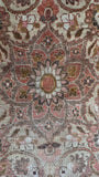 Layered floral medallion in ivory, walnut brown and soft pink on a large antique Tabriz rug.
