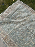 Vintage Persian area rug 7x10 hand knotted in Tabriz with a muted green palette and intricate floral lattice pattern.
