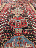 Close-up of a patterned rug with geometric designs in red, blue, and beige.