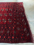 One end of tribal rug with rich, saturated dyes creating a dark and moody palette.