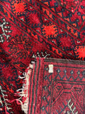 Underside view of a 1970s Afghani rug with deep red tones and soft handle.