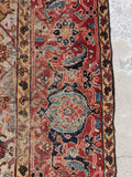 Close up of an antique hallway rug with a narrow ivory field framed by robust, wide decorative borders.
