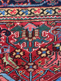 A vintage hand-knotted rug showcases a traditional red and blue Heriz pattern.