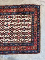 Another one end view of antique Persian rug with tribal and botanical motifs.