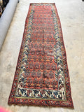 Full overhead view of vintage Persian Kurdish runner rug in brick red and navy