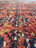 Close-up detail of brick red shrub field pattern on antique Kurdish runner rug showing soft wool pile