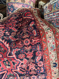 vintage Persian Malayer accent rug draped to show pile depth, navy and coral tribal design