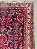 Corner detail of antique Persian Malayer rug showing navy field with saturated coral motifs