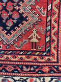 close up female weaver on vintage  Persian runner rug with fish motifs surrounding
