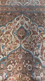 Little ribbons of teal blue tracing floral motifs across a large vintage Persian rug.