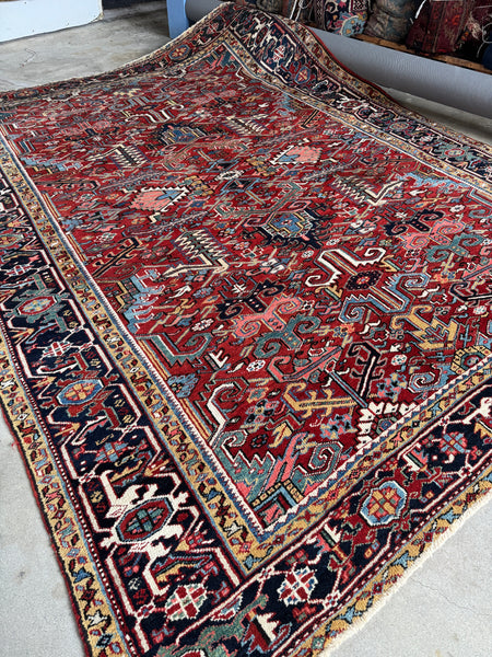 Antique 1930s Persian geometric rug with bold tribal motifs on a rich red field.
