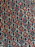 Detail of handwoven Afshar rug showing alternating warm rust and cool blue diamond motifs.