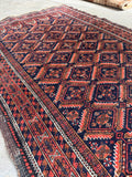1900s antique tribal area rug macro shot illustrating the rich dark blue, rust red, and tan natural dye tones.